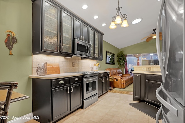 kitchen with ceiling fan with notable chandelier, vaulted ceiling, tasteful backsplash, appliances with stainless steel finishes, and decorative light fixtures