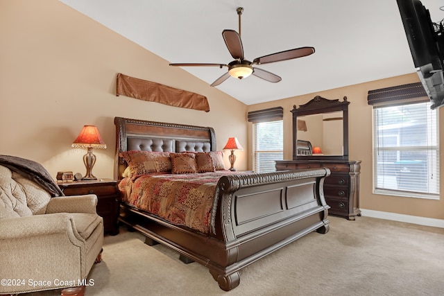 bedroom featuring multiple windows, vaulted ceiling, light colored carpet, and ceiling fan