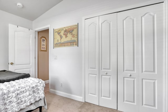 bedroom featuring a closet, lofted ceiling, and light colored carpet