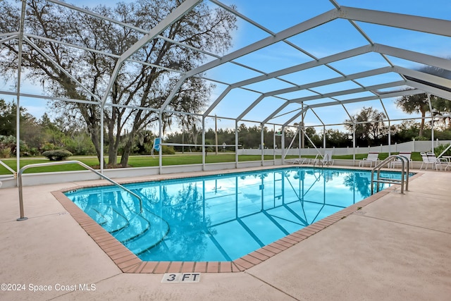 view of swimming pool featuring a patio area, a yard, and a lanai