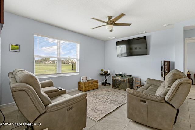 living room with ceiling fan, light tile patterned floors, and a textured ceiling