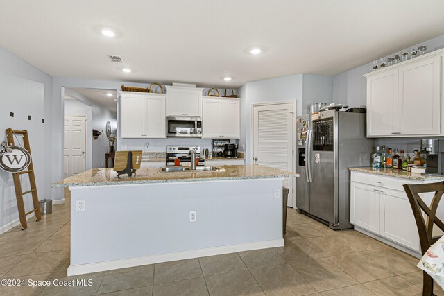 kitchen featuring sink, stainless steel appliances, white cabinetry, and an island with sink