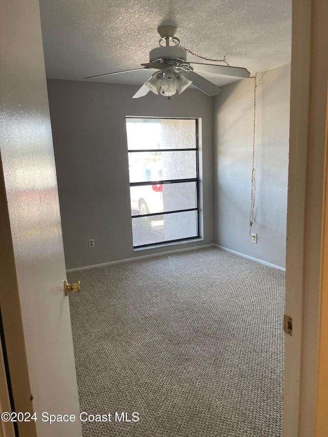 carpeted empty room with a textured ceiling and ceiling fan