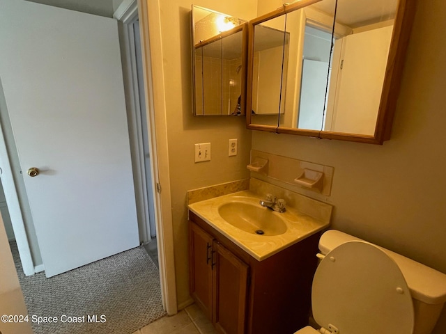 bathroom featuring toilet, vanity, and tile patterned flooring