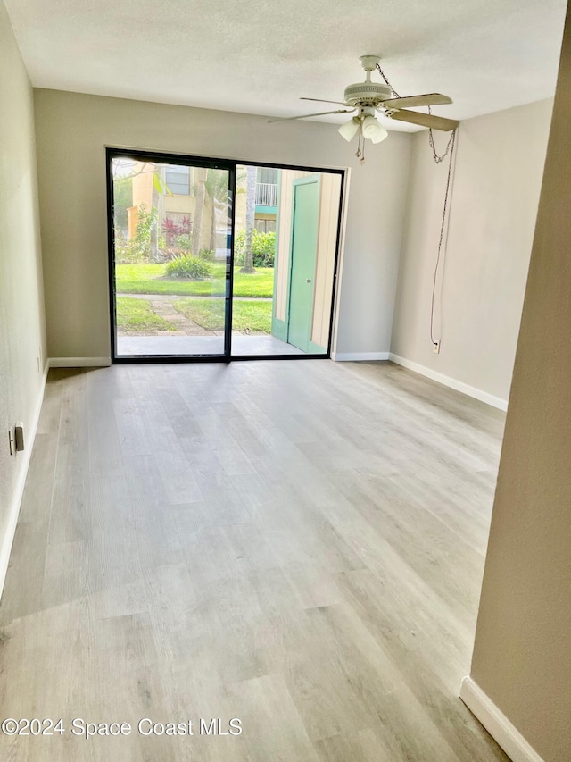 empty room with ceiling fan and light hardwood / wood-style flooring