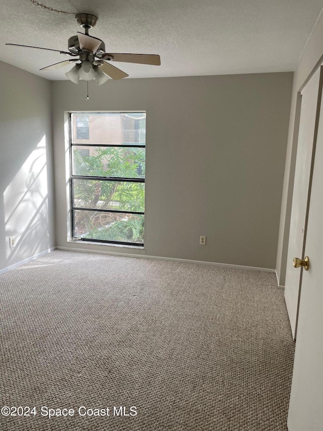 carpeted empty room featuring a textured ceiling and ceiling fan