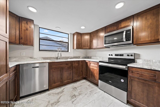 kitchen with dark brown cabinetry, light stone counters, appliances with stainless steel finishes, and sink