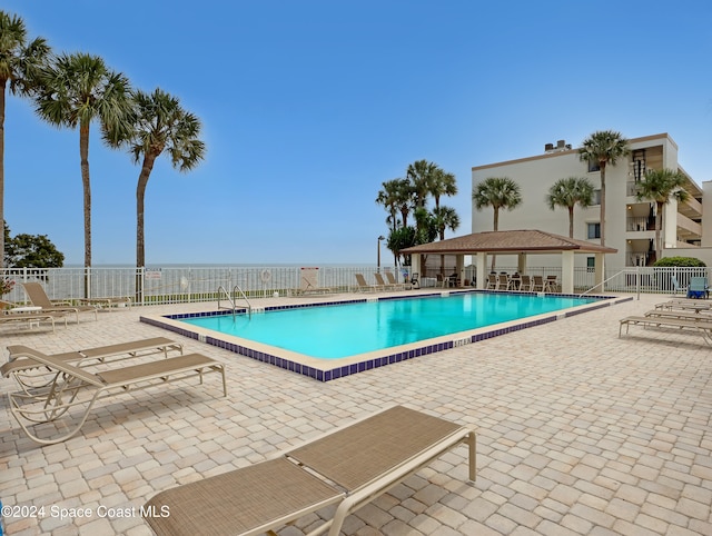 view of swimming pool featuring a patio area and a water view