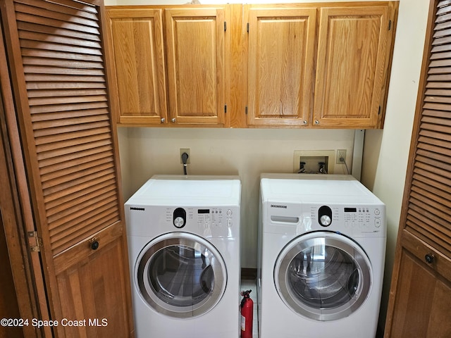 clothes washing area with washing machine and dryer and cabinets