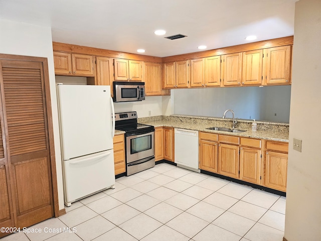 kitchen with light stone counters, stainless steel appliances, sink, and light tile patterned flooring