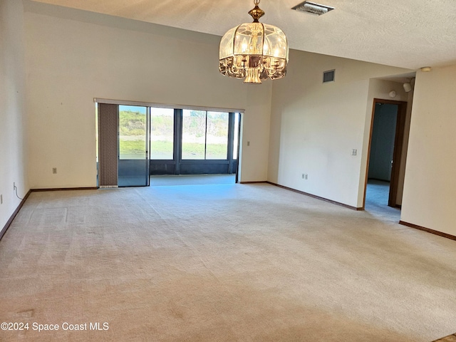 carpeted spare room featuring a textured ceiling and a chandelier