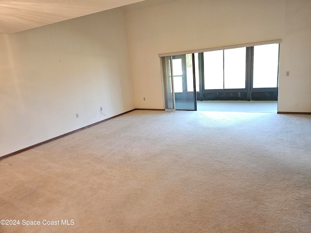 carpeted empty room featuring vaulted ceiling