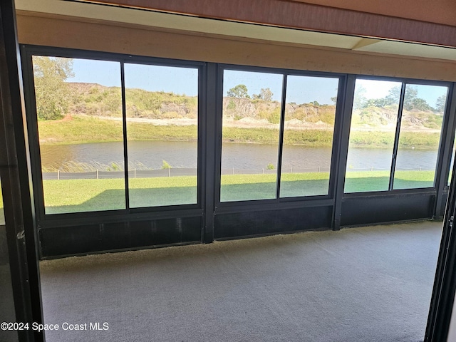 unfurnished sunroom featuring a water view and plenty of natural light