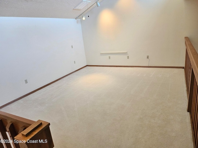 carpeted spare room featuring rail lighting and a textured ceiling