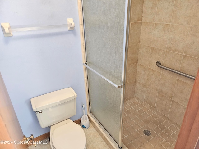 bathroom featuring toilet and a shower with door