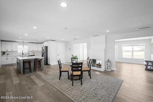 dining space with sink, a fireplace, and wood-type flooring