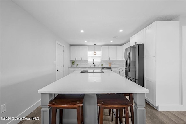 kitchen with dark hardwood / wood-style flooring, stainless steel fridge with ice dispenser, a kitchen bar, pendant lighting, and a center island