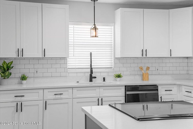 kitchen featuring sink, white cabinets, hanging light fixtures, and backsplash