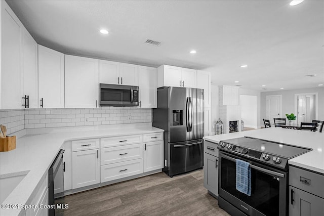 kitchen with white cabinetry, backsplash, stainless steel appliances, and dark wood-type flooring