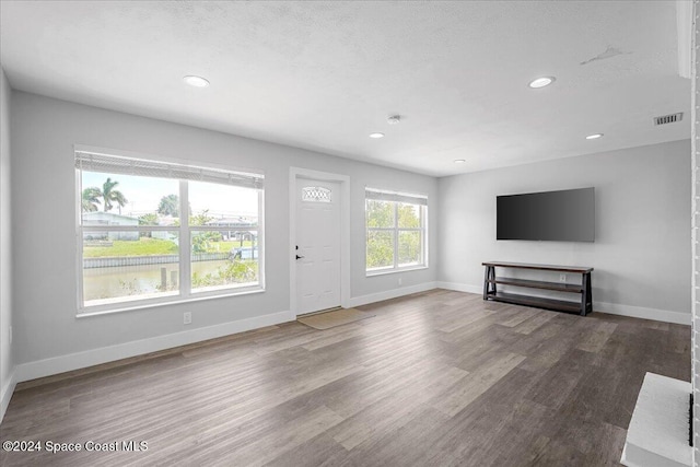 unfurnished living room with wood-type flooring and a textured ceiling