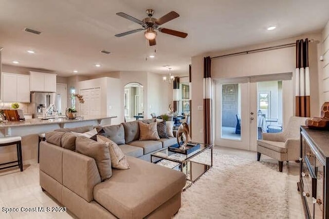 living room featuring french doors and ceiling fan with notable chandelier