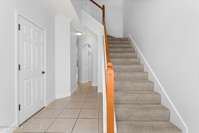 staircase with crown molding and tile patterned floors