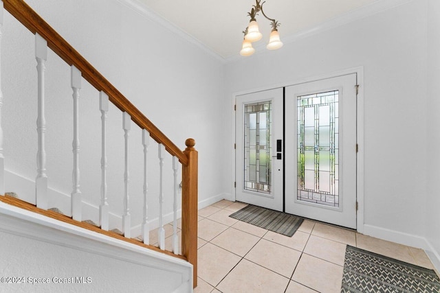 tiled entryway featuring french doors, crown molding, and an inviting chandelier