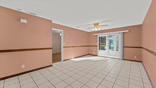 spare room featuring a textured ceiling, light tile patterned flooring, and ceiling fan