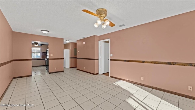 tiled empty room featuring a textured ceiling and ceiling fan