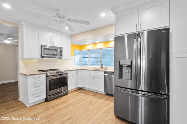 kitchen featuring appliances with stainless steel finishes, tasteful backsplash, light stone counters, light hardwood / wood-style floors, and white cabinetry