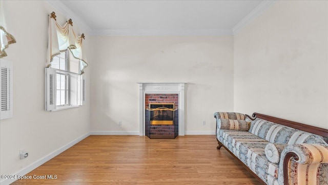 living room with crown molding, light wood-type flooring, and a brick fireplace