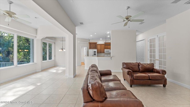 living room featuring french doors, light tile patterned floors, and ceiling fan with notable chandelier