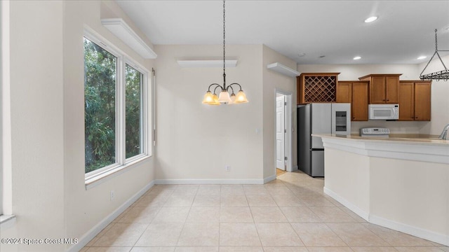 kitchen with an inviting chandelier, hanging light fixtures, plenty of natural light, and stainless steel refrigerator