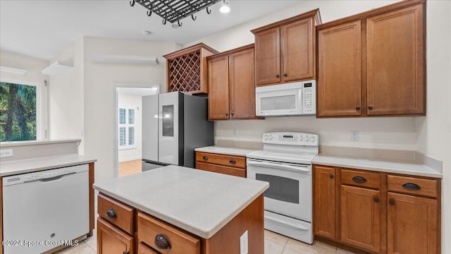 kitchen featuring a center island, light tile patterned floors, and white appliances