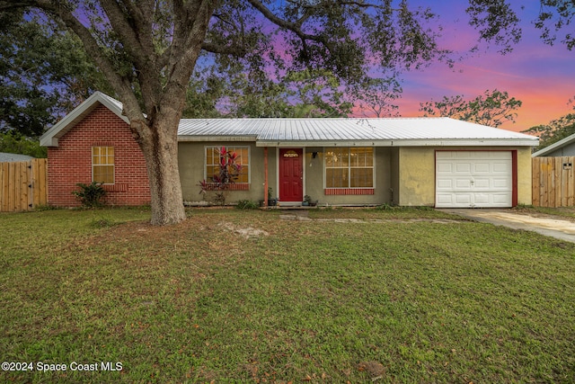 single story home featuring a garage and a yard