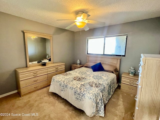 bedroom featuring light carpet, a textured ceiling, and ceiling fan