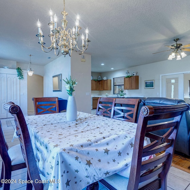 dining space with ceiling fan with notable chandelier, light hardwood / wood-style floors, and a textured ceiling