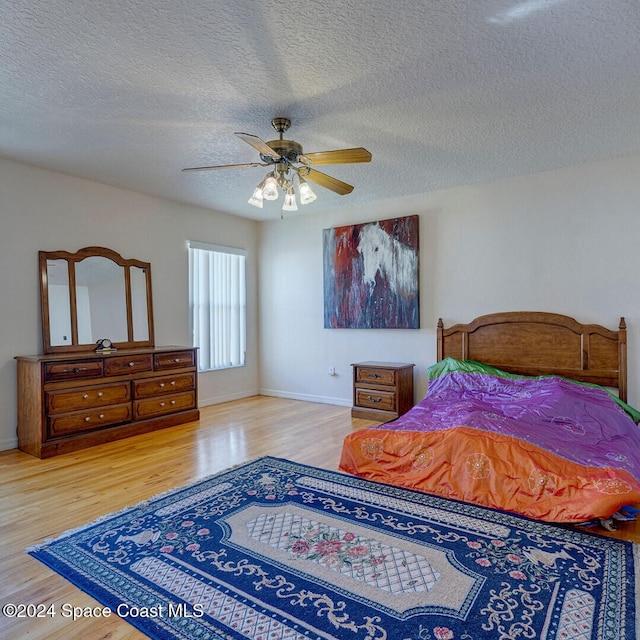 bedroom with ceiling fan, light hardwood / wood-style floors, and a textured ceiling