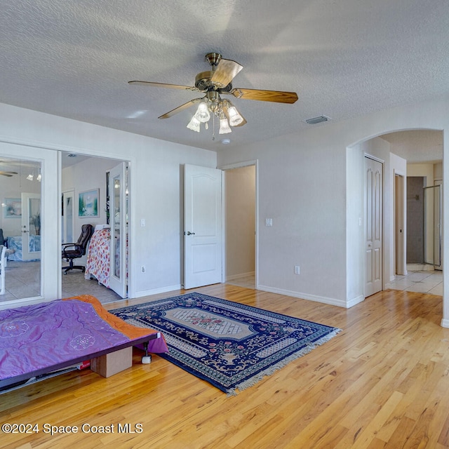 bedroom with hardwood / wood-style flooring, ceiling fan, a textured ceiling, and a closet