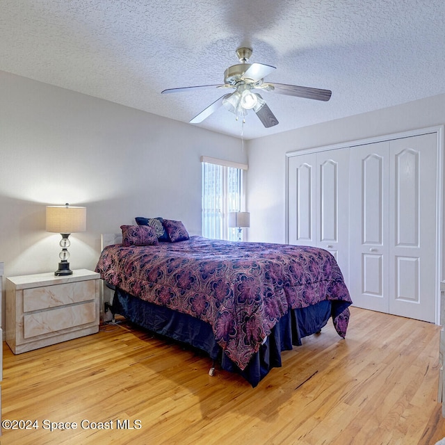 bedroom featuring a closet, ceiling fan, light hardwood / wood-style flooring, and a textured ceiling