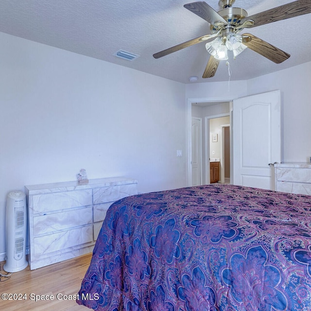 bedroom with a textured ceiling, light hardwood / wood-style flooring, and ceiling fan