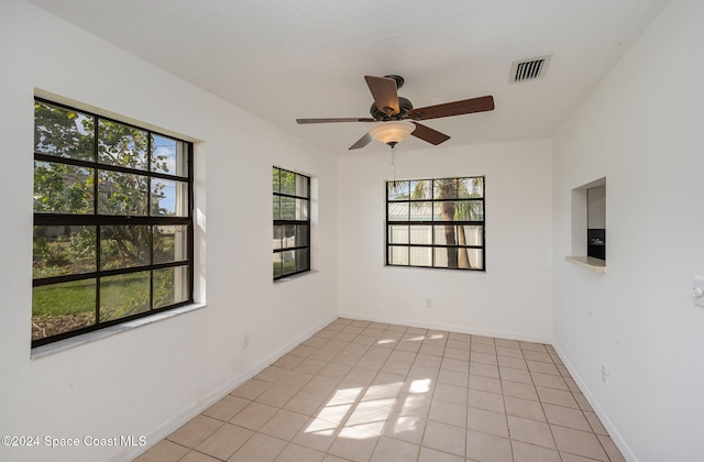 unfurnished room with light tile patterned flooring, a wealth of natural light, and ceiling fan