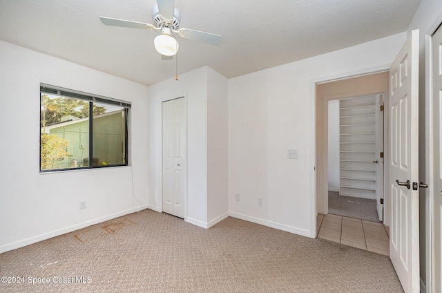 unfurnished bedroom featuring ceiling fan, light carpet, and a closet