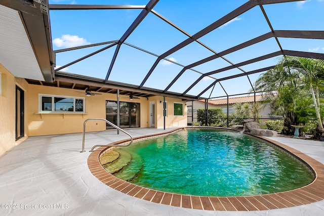 view of swimming pool featuring ceiling fan, a patio, and glass enclosure