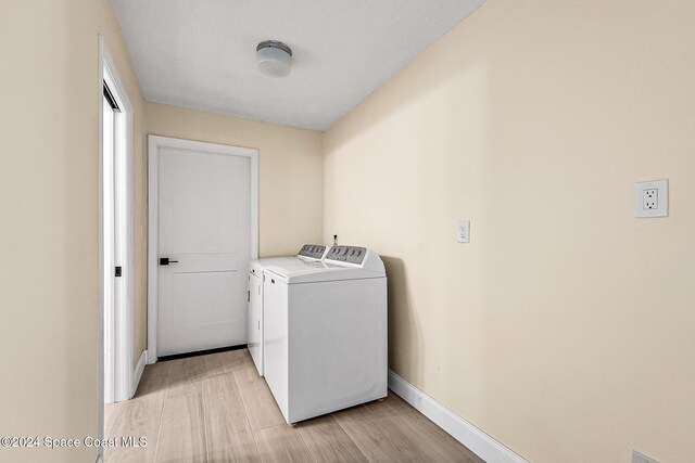 laundry area with light hardwood / wood-style flooring and washer and dryer