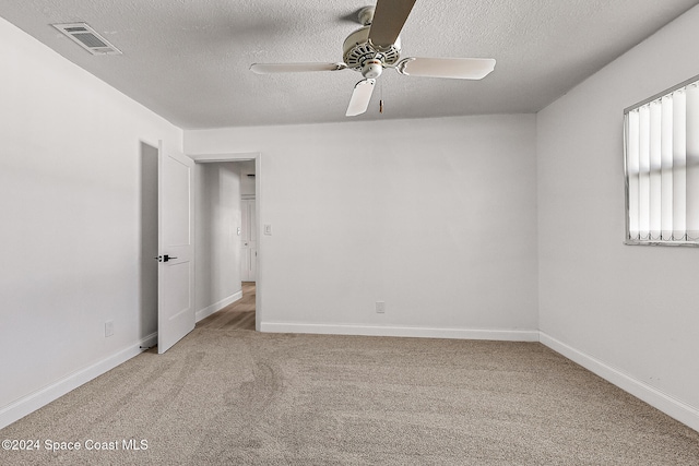 empty room with ceiling fan, carpet flooring, and a textured ceiling