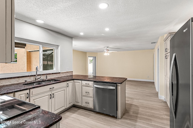 kitchen featuring sink, light hardwood / wood-style flooring, appliances with stainless steel finishes, kitchen peninsula, and backsplash