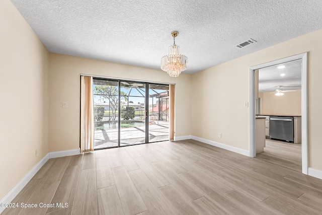 spare room with a textured ceiling, a notable chandelier, and light wood-type flooring