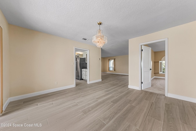 unfurnished living room with a notable chandelier and a textured ceiling