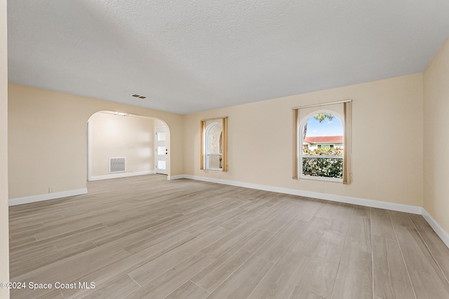 empty room with a textured ceiling and light wood-type flooring